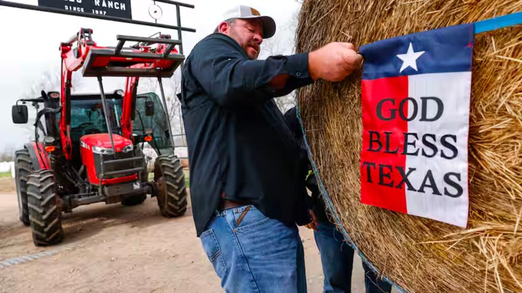 Lee Wells tightens God Bless Texas flag around a haybail